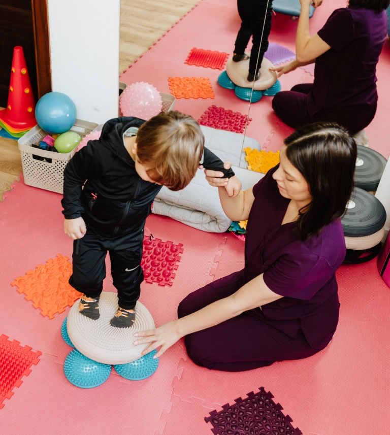 chłopiec stojący na&nbsp;akcesoriach rehabilitacyjnych